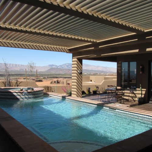 a louvered patio covering shading a residential swimming pool