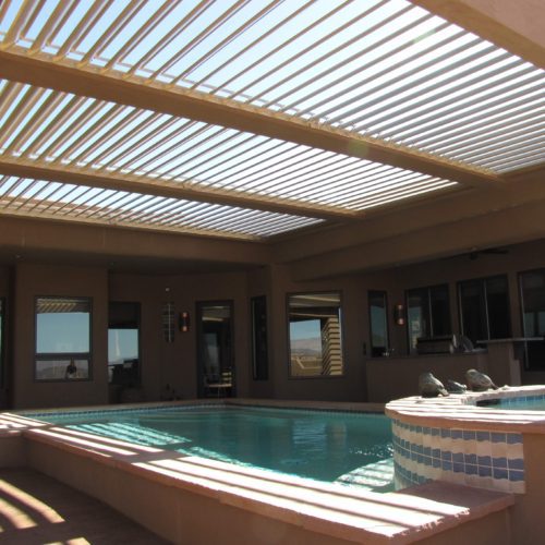 A pool in a residential backyard being shaded by an Equinox louvered patio cover