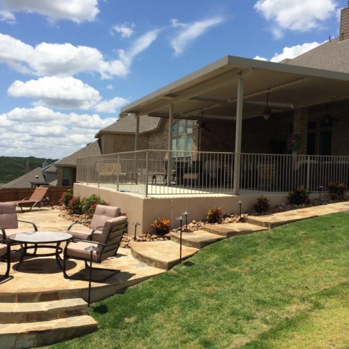 stone steps leading up to a white patio covering in a residential backyard