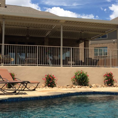 a residential backyard with a louvered patio covering