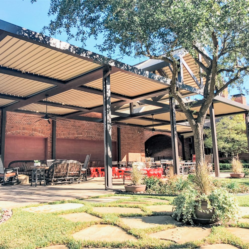 A large faux wood pergola with black columns in a residential backyard