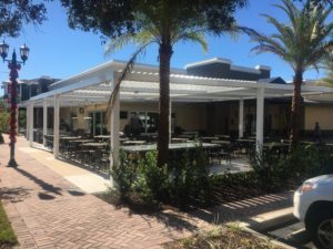 A restaurant outdoor patio shaded by a white pergola