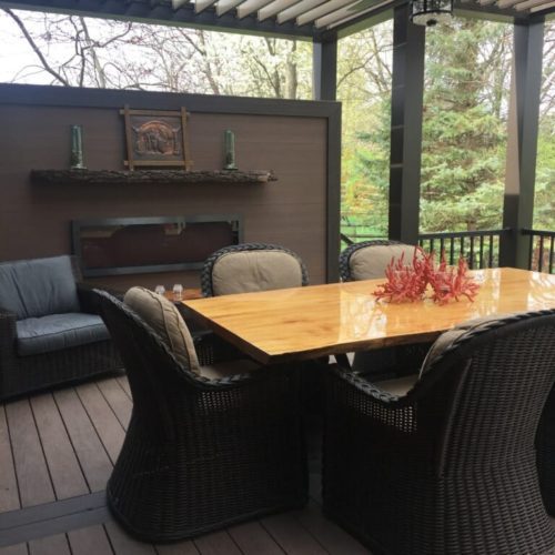 a black faux wood patio covering in a residential backyard with a wooden table and dark furniture