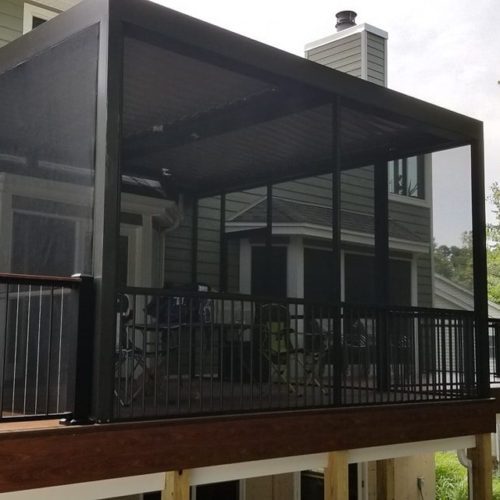 A residential backyard deck enclosed in a black patio enclosure by Equinox