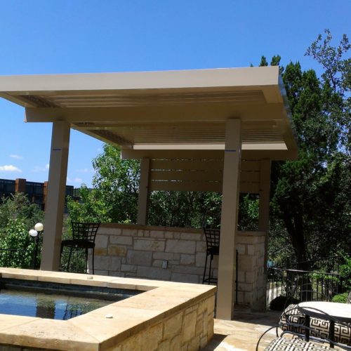 A small louvered pergola shading an outdoor seating area in a small backyard