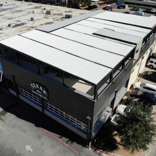 Overhead view of a white metal roofing system shading a commercial outdoor patio