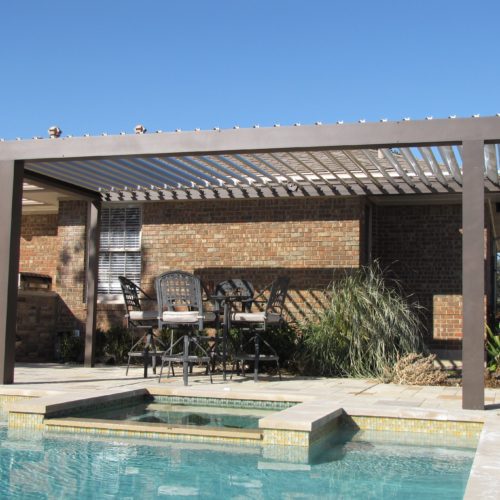 Outdoor open louvered patio covering and pool in the backyard of an island home