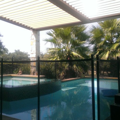 an outdoor pool in a residential backyard being shaded by an equinox louvered patio cover 