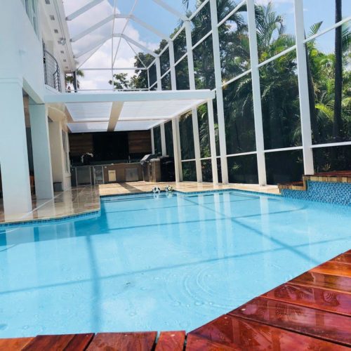 a white pergola shading an indoor pool in a residential backyard