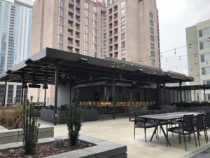 Outdoor dining area on the roof of a commercial building with a black faux wood pergola by equinox