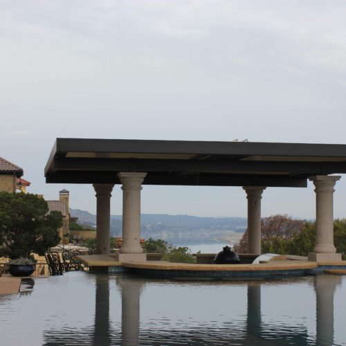 a custom 4 column pergola provides shade to the pool area in a residential backyard. 