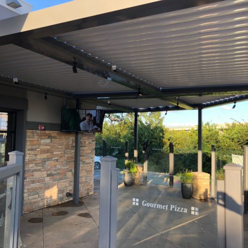 A motorized louvered patio cover provides shade to a commercial business