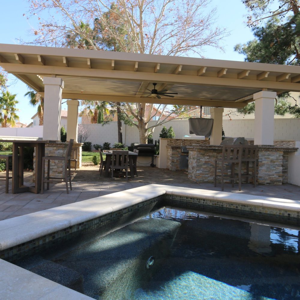 a pergola covers a backyard pool deck area