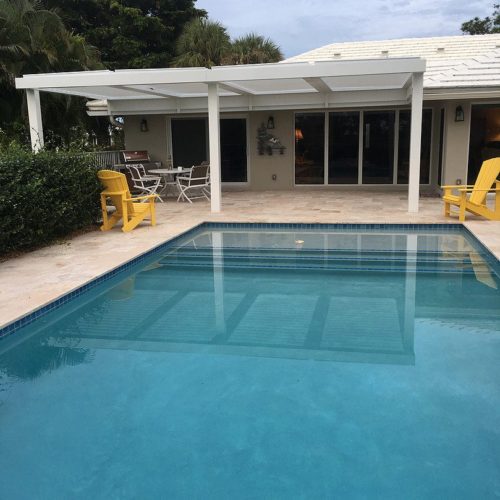 Outdoor louvered patio covering in residential backyard pool area