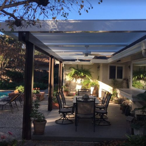 Outdoor louvered patio covering outdoor dining area in residential backyard 