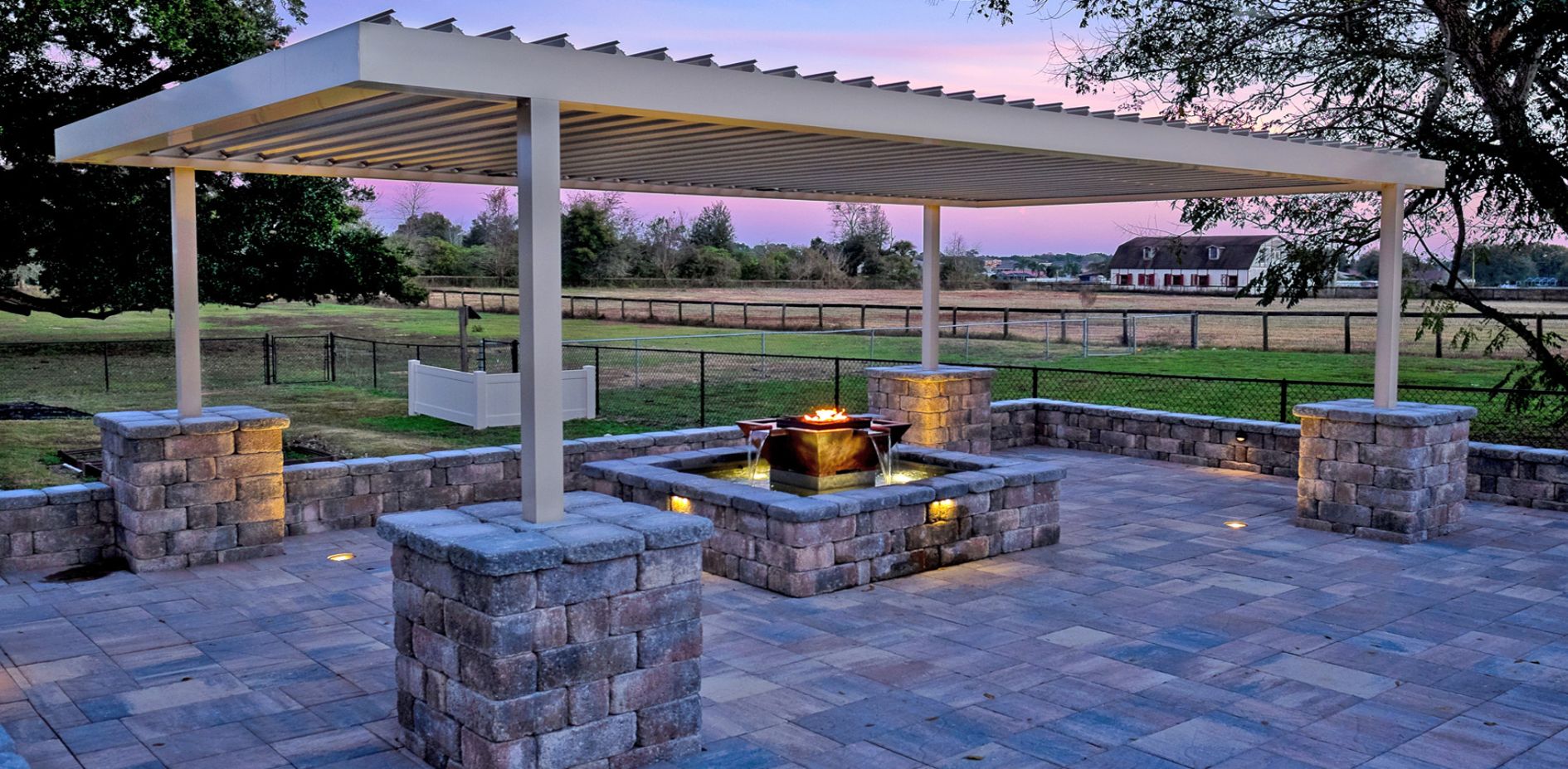 A pergola shades an outdoor seating area in the sunset