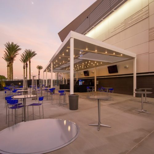 An equinox pergola shades an outdoor seating area in a commercial space